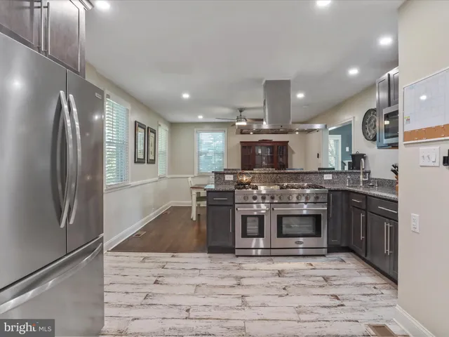 a kitchen with stainless steel appliances granite countertop a stove top oven a sink and a refrigerator
