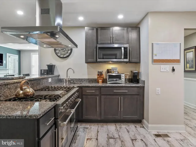 a kitchen with kitchen island granite countertop a sink and a stove