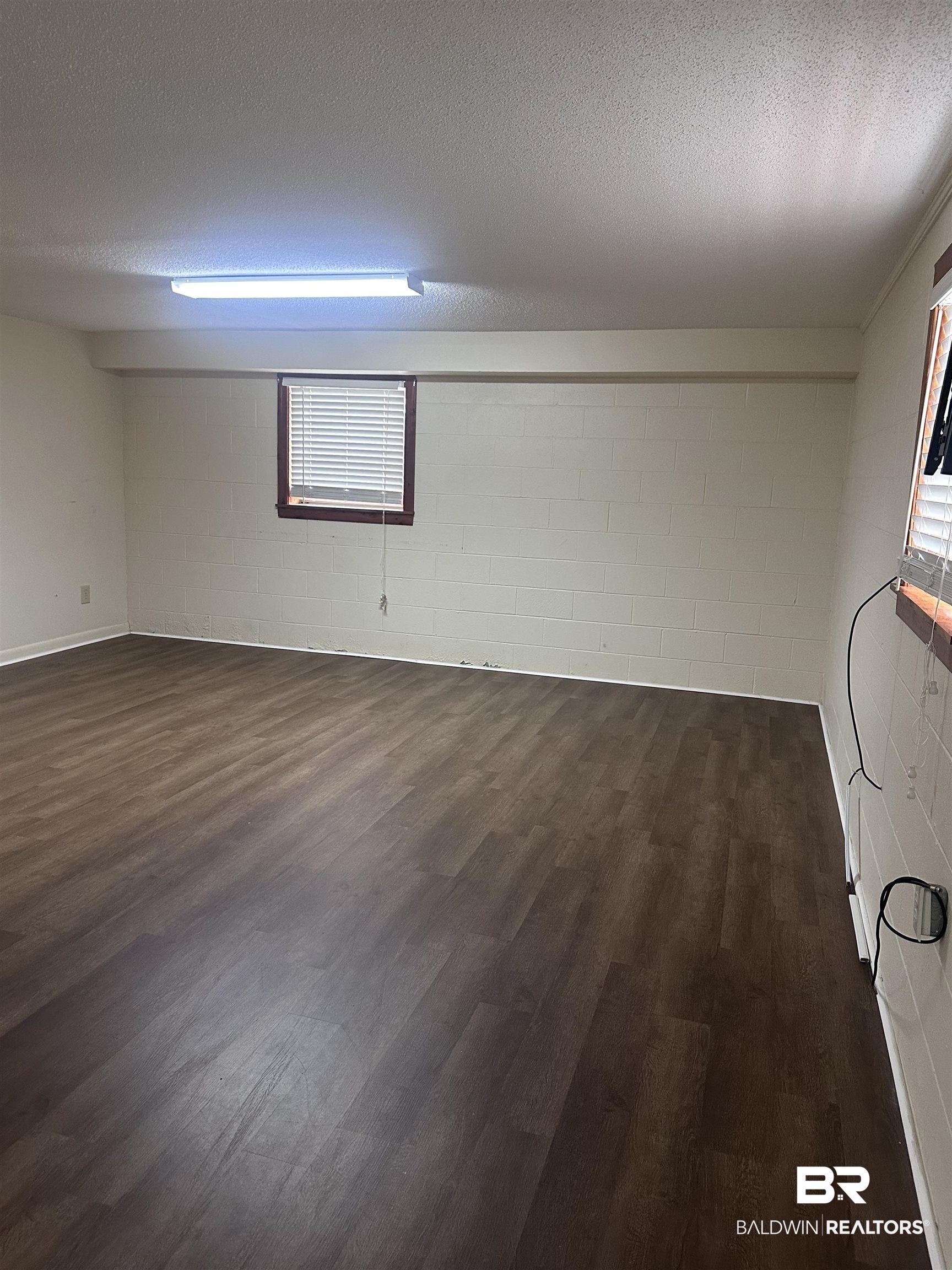 2785 Sowell Road Brewton, AL 36426 - Photo 22 of 24 Spare room with concrete block wall, a textured ceiling, and dark wood finished floors