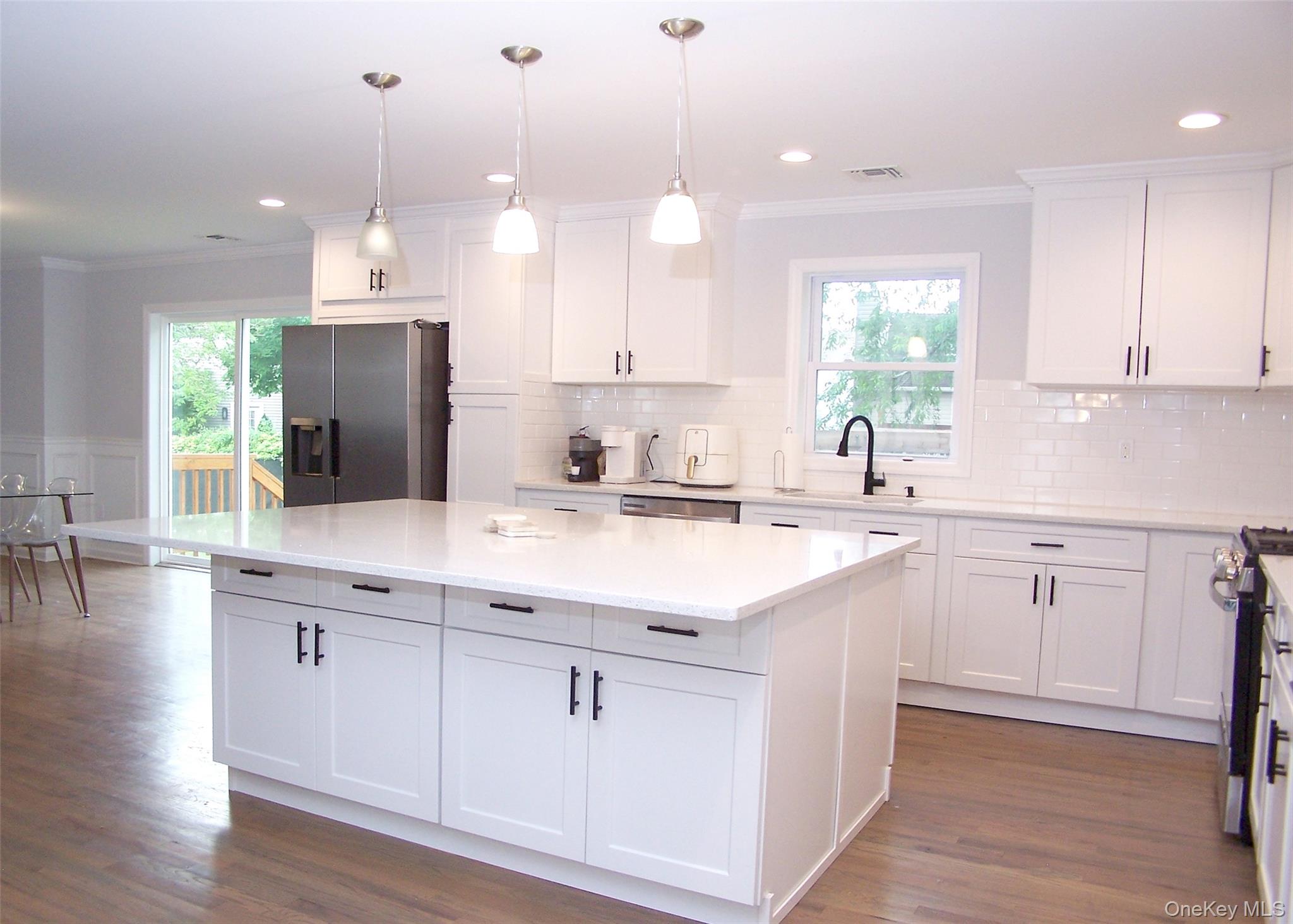 8 Narcissus Road Mastic Beach, NY 11951 - Photo 10 of 20 a kitchen with kitchen island granite countertop a sink a counter space appliances and cabinets