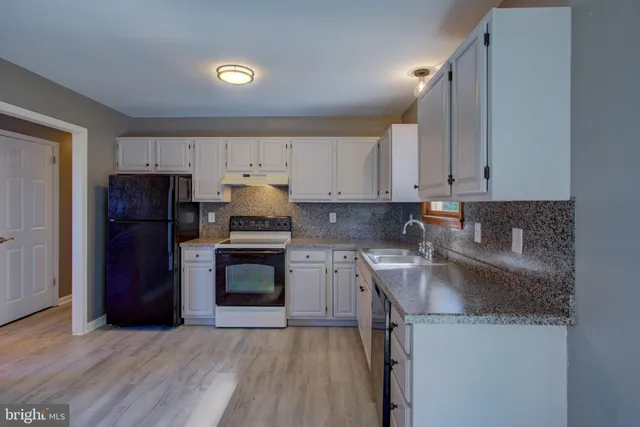 a kitchen with granite countertop a sink cabinets stainless steel appliances and a window