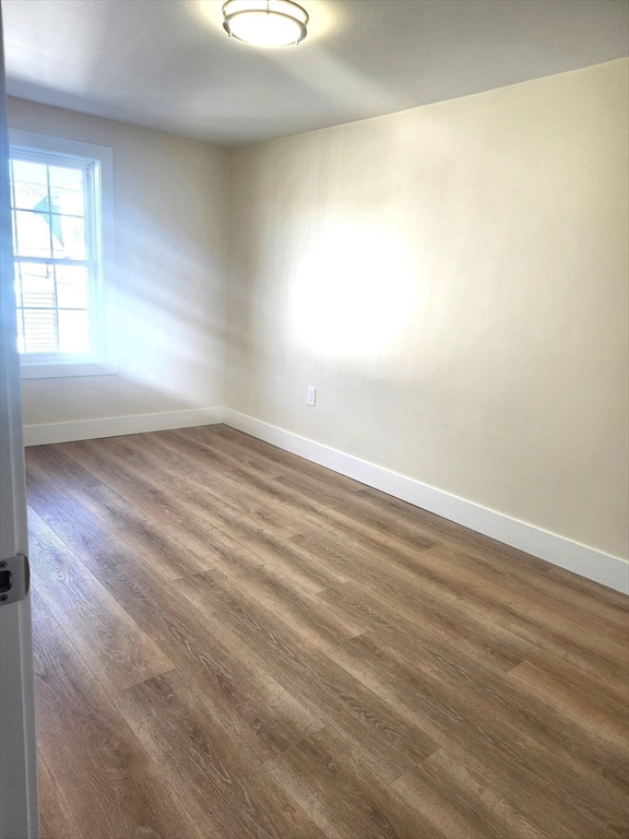264 Bowen Street, Unit 264 Boston, MA 02127 - Photo 10 of 18 an empty room with wooden floor and windows