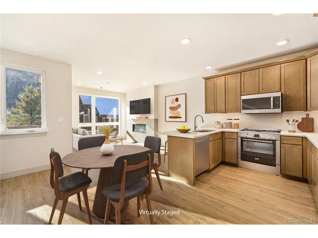a large kitchen with a table chairs wooden cabinets and stainless steel appliances