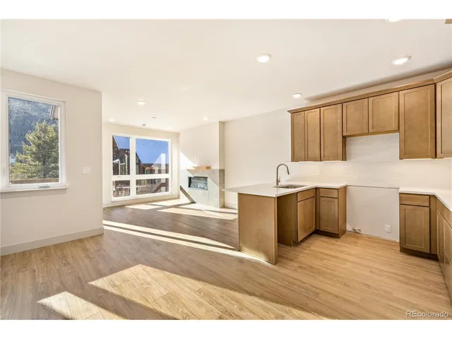a view of a kitchen with a sink wooden cabinets and a window