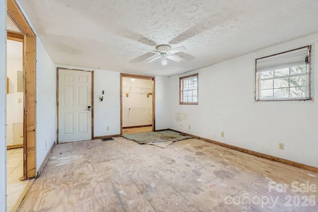 an empty room with windows and ceiling fan