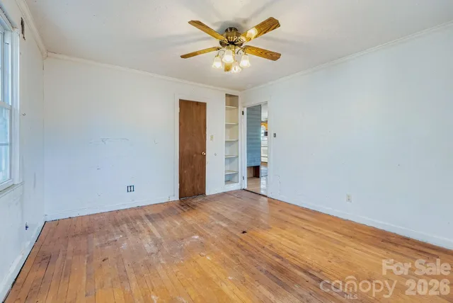 a view of a big room with wooden floor and a chandelier fan