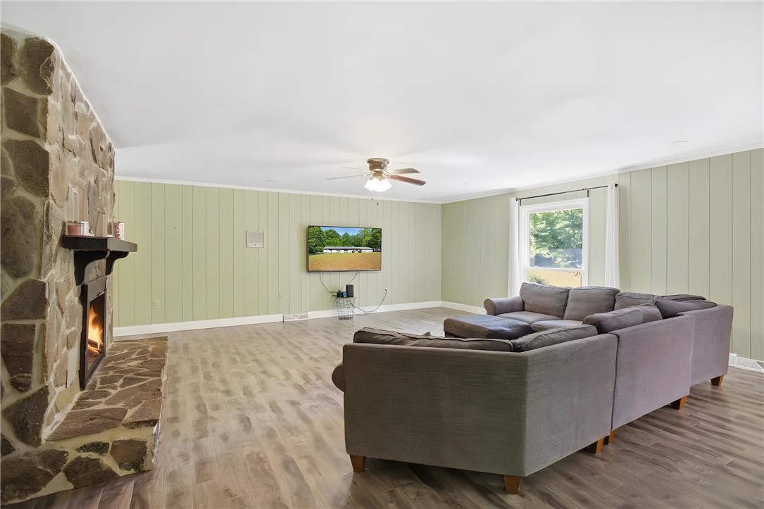 311 Cumberland Way Anderson, SC 29621 - Photo 3 of 44 A well-lit living space features a stone fireplace and light wood-look flooring.
