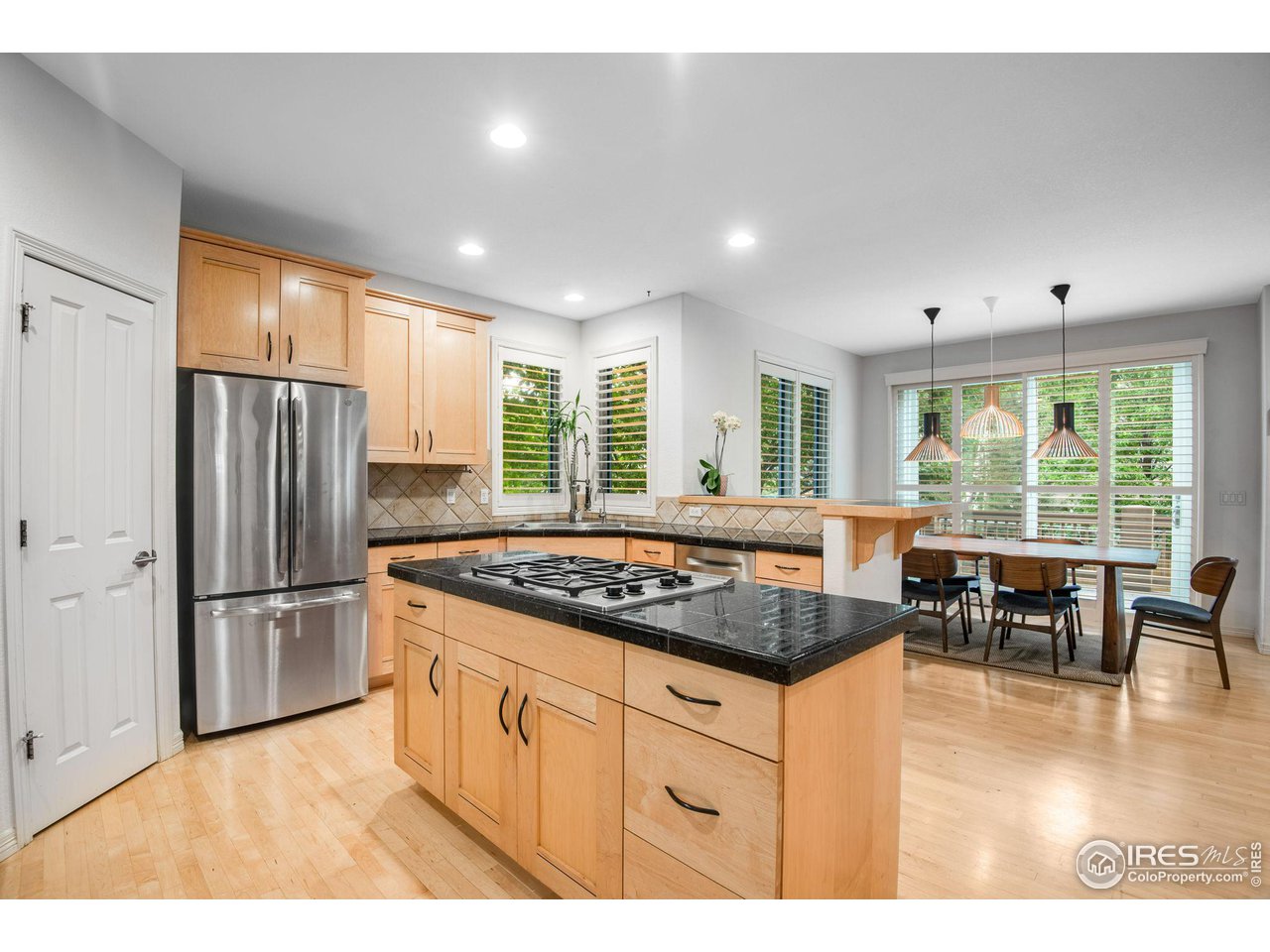 4026 Nevis Street Boulder, CO 80301 - Photo 12 of 40 a kitchen with stainless steel appliances granite countertop a stove a refrigerator a sink a dining table and chairs with wooden floor