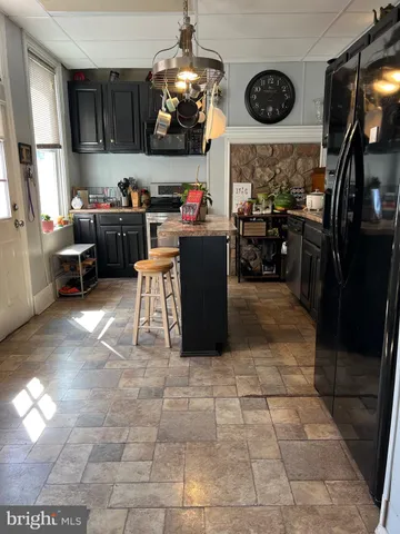 a kitchen with granite countertop a refrigerator stove and wooden cabinets