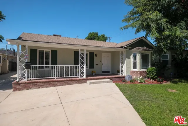 a backyard of a house with plants and large tree