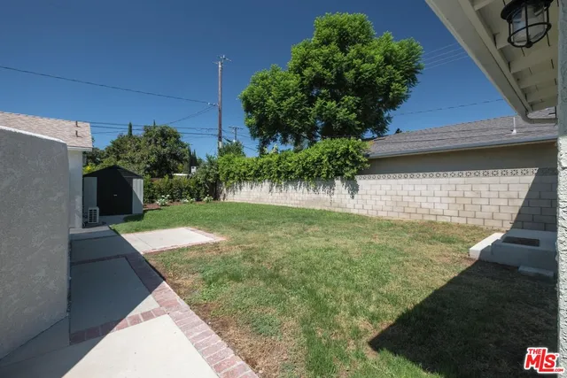 a view of backyard with potted plants and a wooden fence