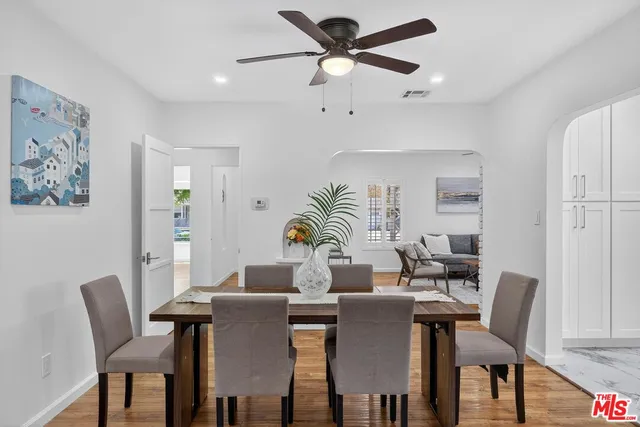 a kitchen with stainless steel appliances a sink stove and white cabinets with wooden floor