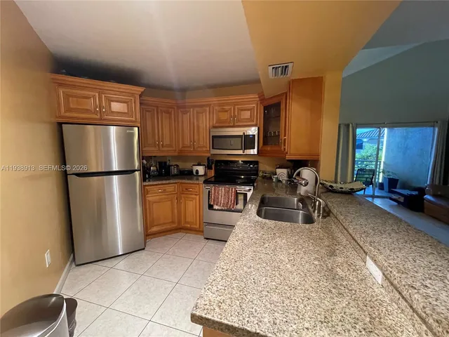 a kitchen with granite countertop a refrigerator and a sink