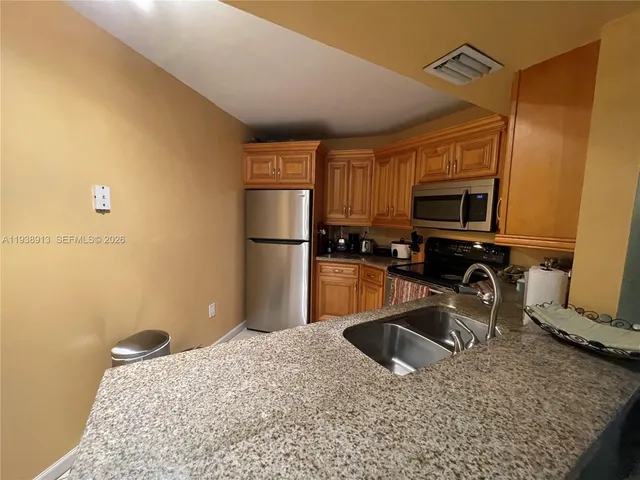 a kitchen with stainless steel appliances granite countertop a refrigerator a stove a sink and a granite counter tops