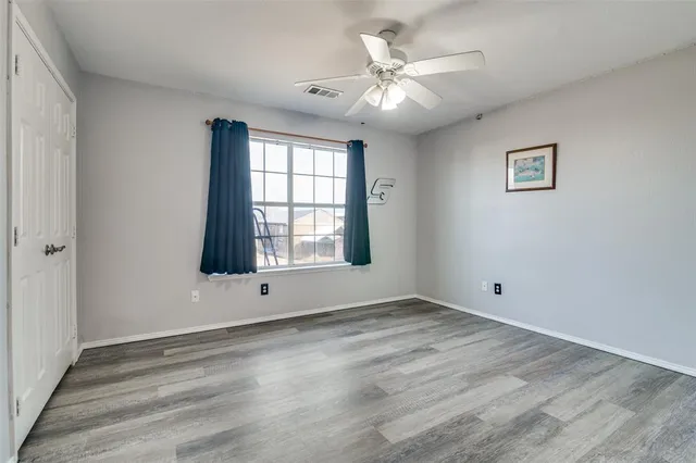 a view of an empty room with a window and wooden floor