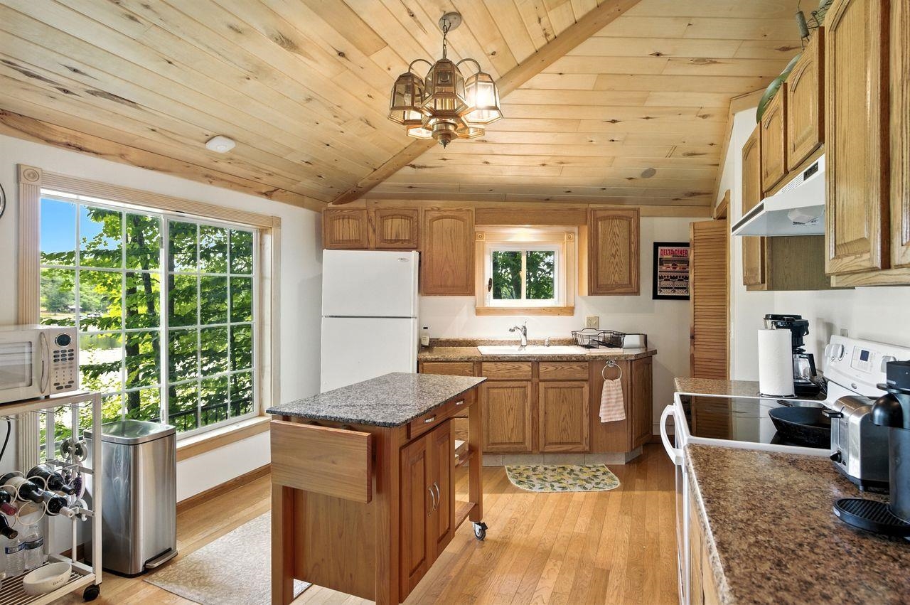 10570 Eagle Lake Road Delta, WI 54847 - Photo 11 of 24 Kitchen featuring white appliances, hanging light fixtures, light wood finished floors, brown cabinetry, and a center island