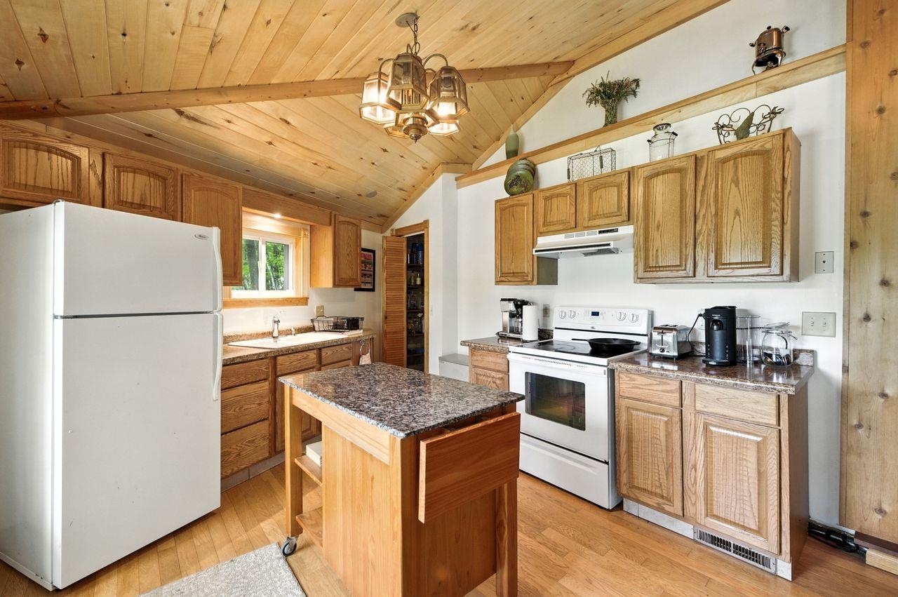 10570 Eagle Lake Road Delta, WI 54847 - Photo 12 of 24 Kitchen with white appliances, pendant lighting, a chandelier, light wood finished floors, and wood ceiling