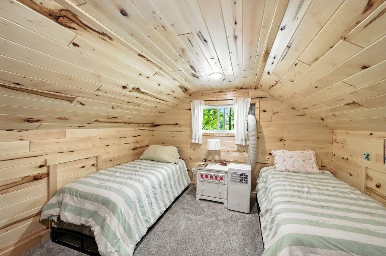 10570 Eagle Lake Road Delta, WI 54847 - Photo 14 of 24 Carpeted bedroom featuring wood ceiling, lofted ceiling, and wooden walls