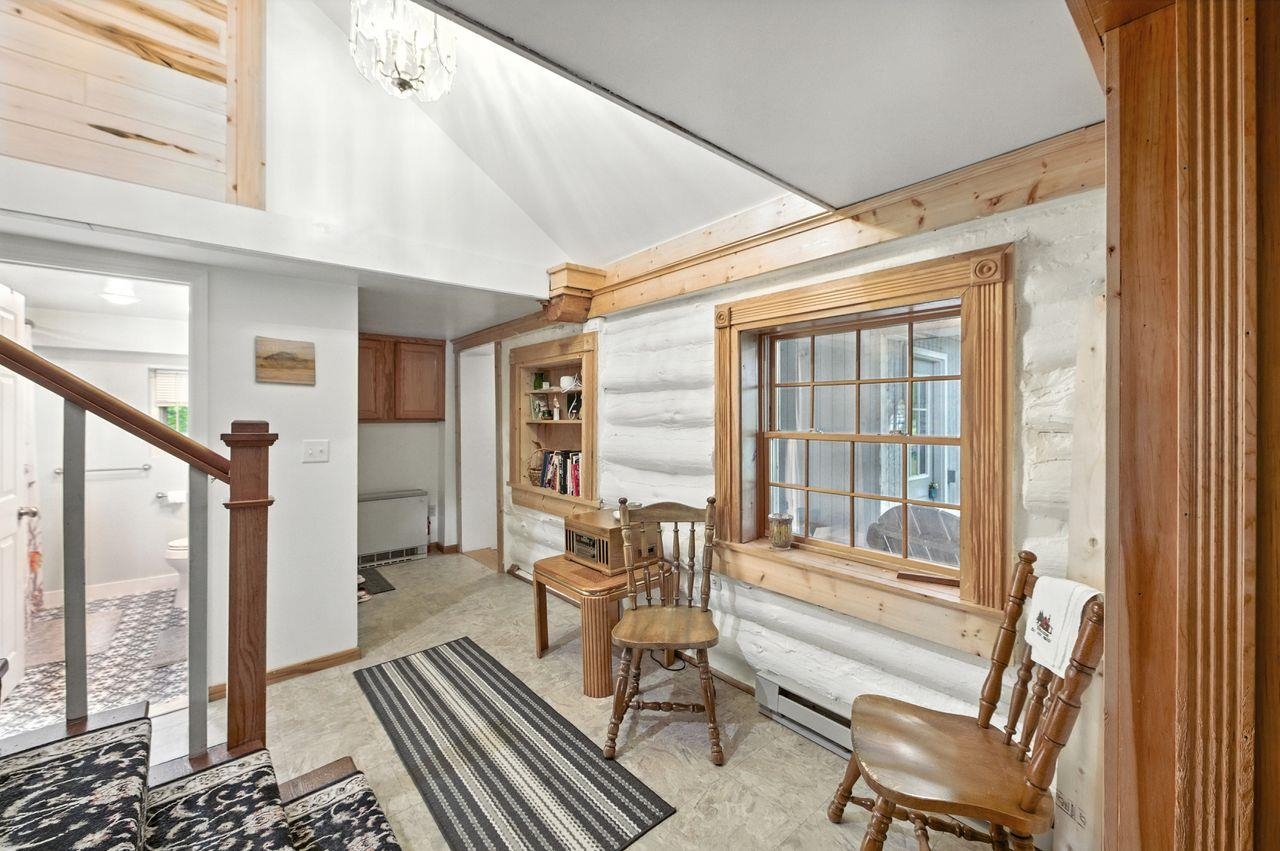 10570 Eagle Lake Road Delta, WI 54847 - Photo 3 of 24 Living area featuring lofted ceiling, a baseboard radiator, stairs, and a chandelier