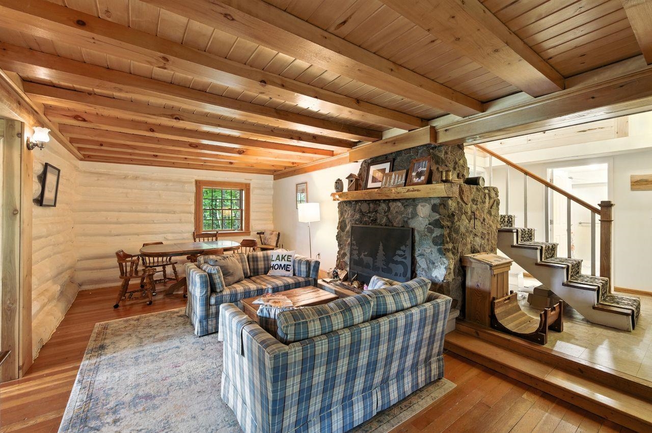 10570 Eagle Lake Road Delta, WI 54847 - Photo 4 of 24 Living area featuring hardwood / wood-style floors, a stone fireplace, and a wood ceiling with exposed beams