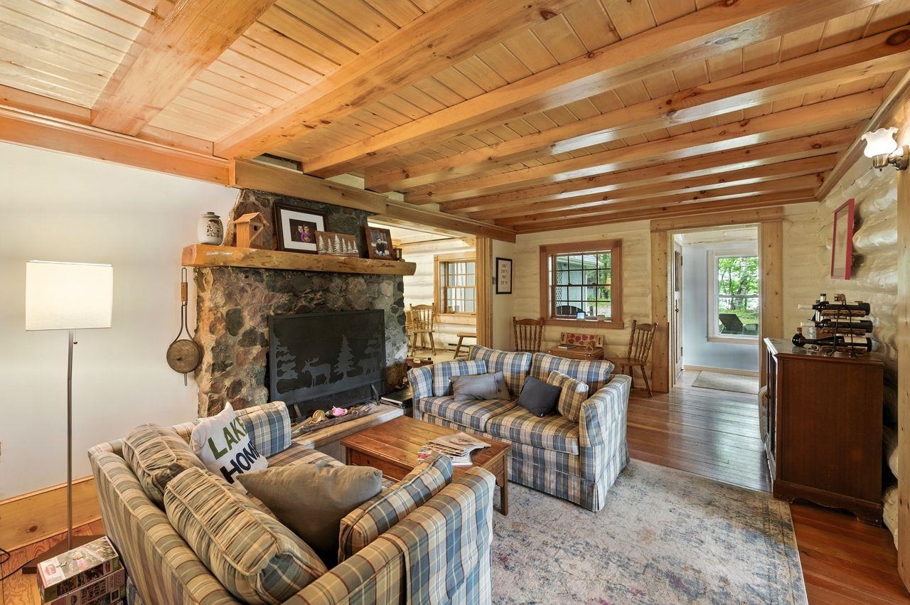 10570 Eagle Lake Road Delta, WI 54847 - Photo 5 of 24 Living area with wood finished floors, a stone fireplace, and a wooden ceiling with exposed beams
