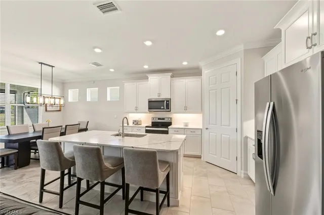 a kitchen with stainless steel appliances granite countertop a refrigerator a sink a stove a dining table and chairs