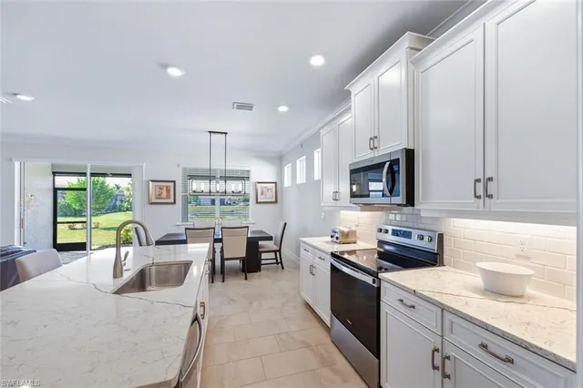 a kitchen with stainless steel appliances granite countertop a stove top oven a sink dishwasher a dining table and chairs with wooden floor