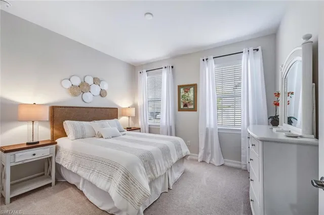 a large white bed in a bedroom next to a window