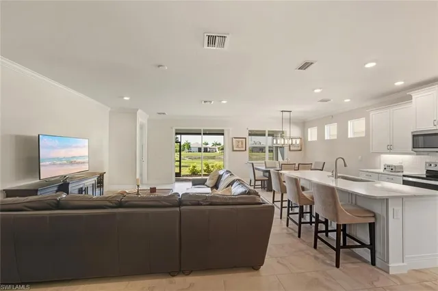 a living room with furniture kitchen view and a large window