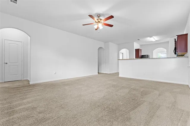 a view of a livingroom with a ceiling fan and kitchen space