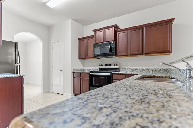 a kitchen with granite countertop a refrigerator stove and microwave