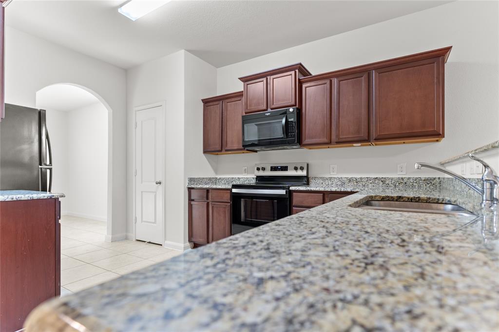 1815 Hot Springs Way Princeton, TX 75407 - Photo 10 of 22 a kitchen with granite countertop a refrigerator stove and microwave
