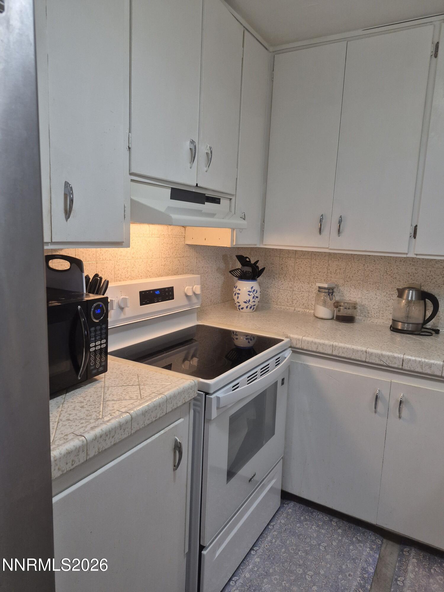 3280 Lone Tree Road Fallon, NV 89406 - Photo 40 of 59 a kitchen with granite countertop white cabinets and white appliances