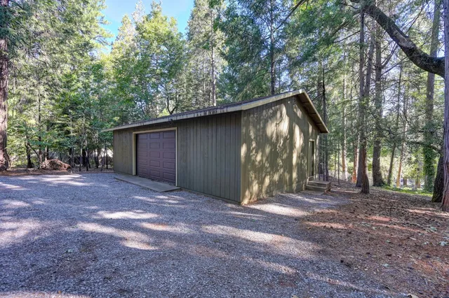 a view of a barn with large trees and a small barn