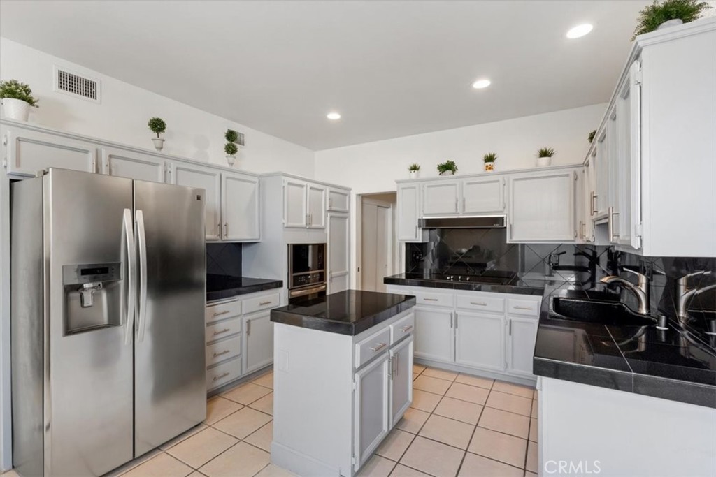 77 Lakeshore Drive Rancho Mirage, CA 92270 - Photo 8 of 25 a kitchen with a refrigerator a sink and white cabinets