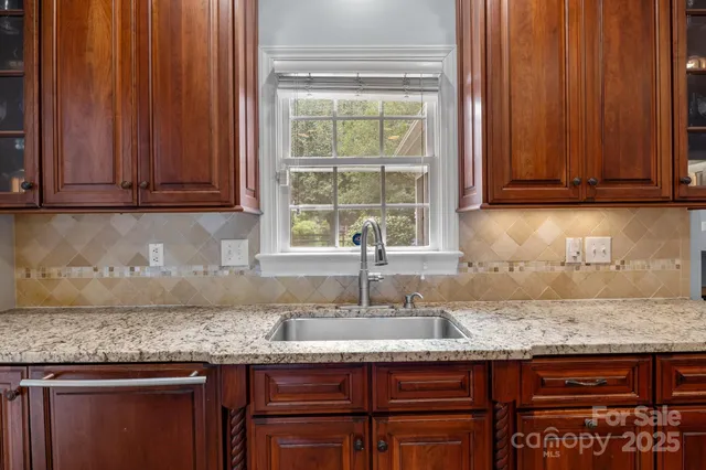 a kitchen with granite countertop wooden cabinets a sink and a window