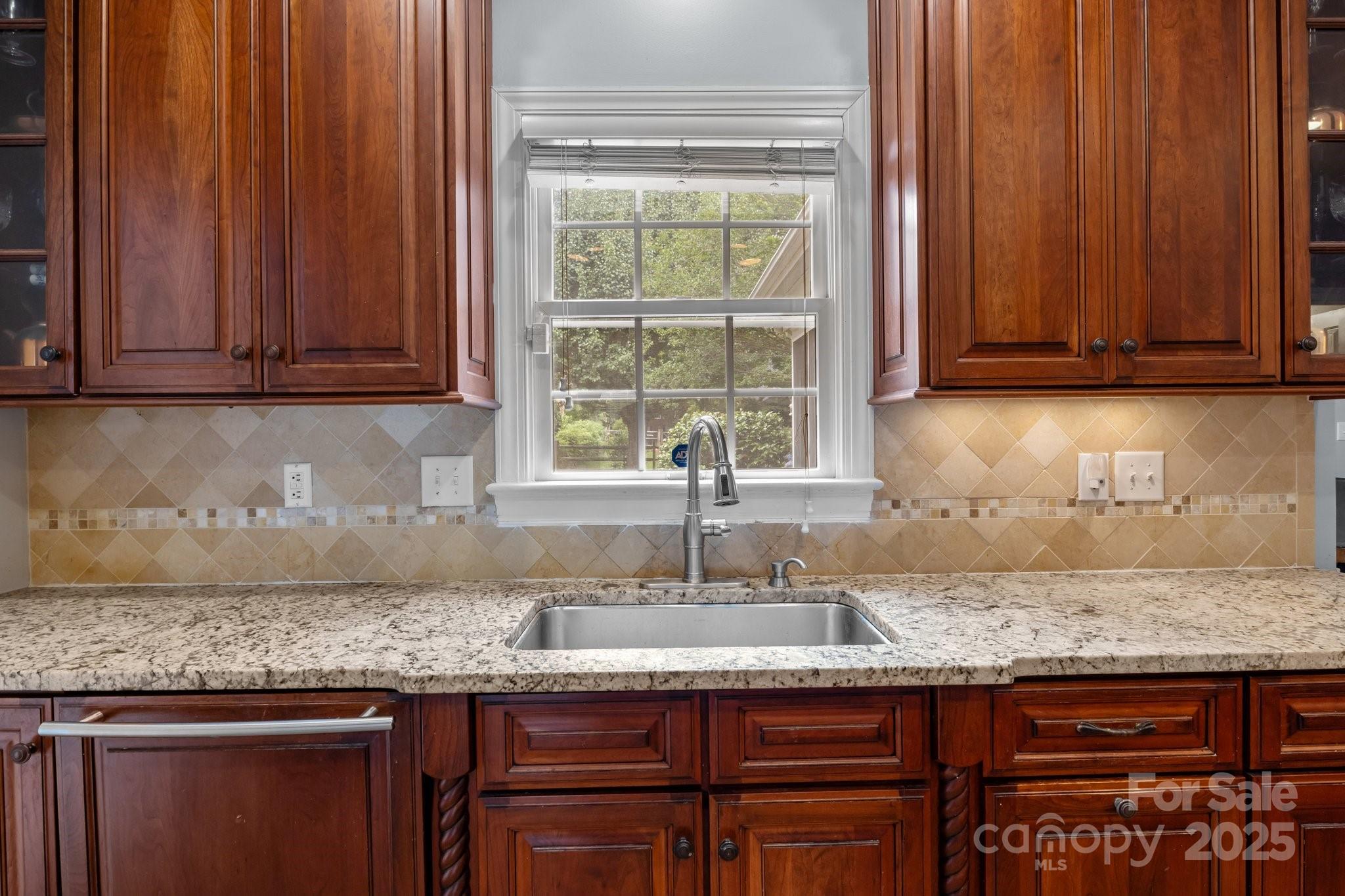 9717 Waterton Court Huntersville, NC 28078 - Photo 15 of 47 a kitchen with granite countertop wooden cabinets a sink and a window