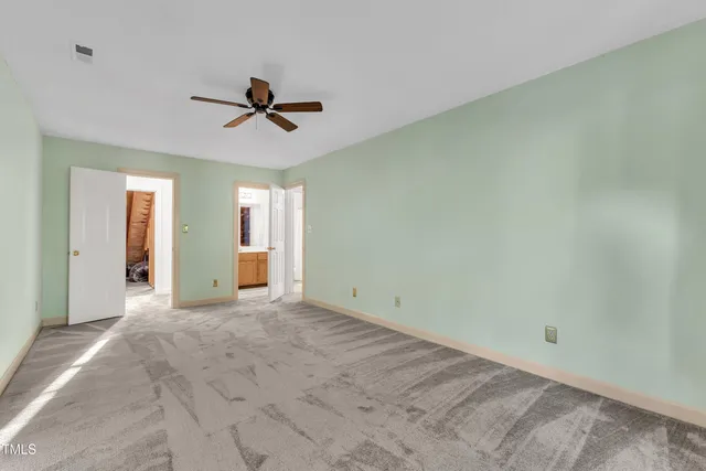 an empty room with chandelier fan and windows