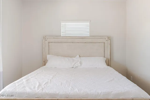 a bedroom with a white bed and a window
