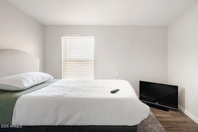 a bedroom with a bed a tv and wooden floor