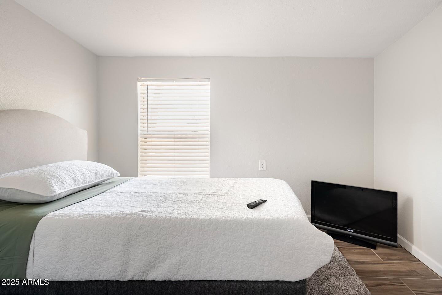 1514 East Fillmore Street Phoenix, AZ 85006 - Photo 17 of 24 a bedroom with a bed a tv and wooden floor