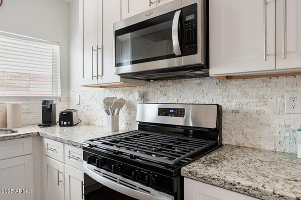 a kitchen with granite countertop stainless steel appliances a sink stove and microwave