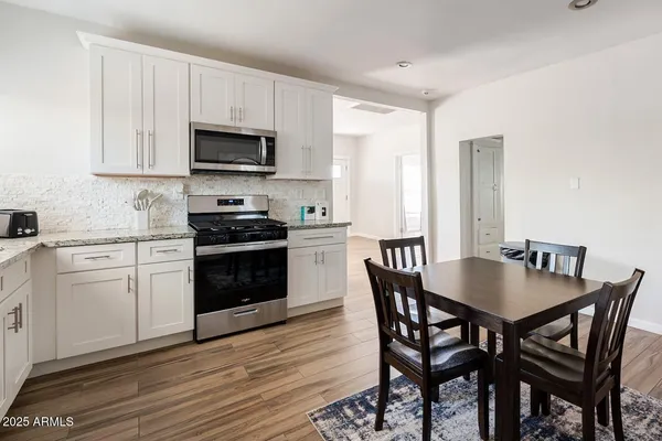 a kitchen with stainless steel appliances a stove a sink dishwasher a microwave oven with a dining table and chairs