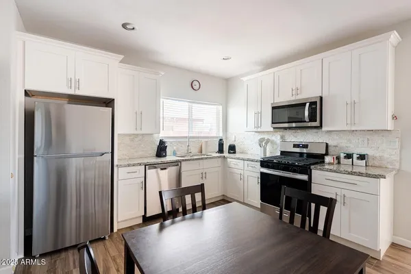 a kitchen with white cabinets and stainless steel appliances