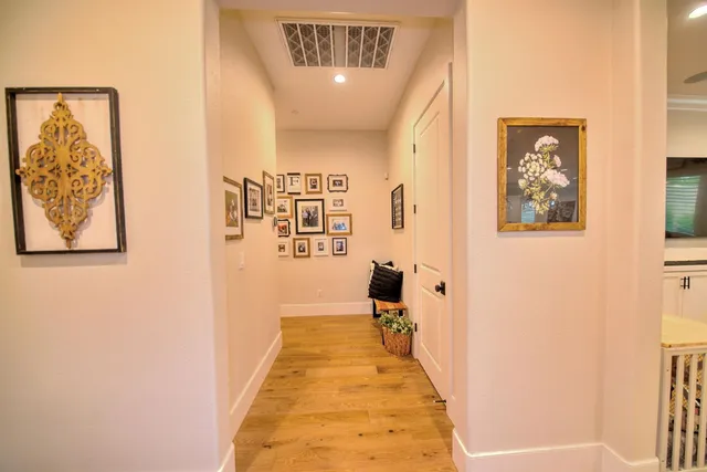 a hallway with painting on the wall and a large mirror