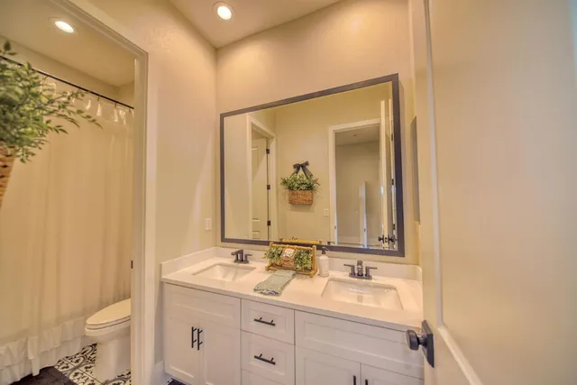 a bathroom with a double vanity sink toilet and mirror