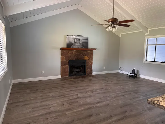 a view of an empty room with a fireplace and wooden floor
