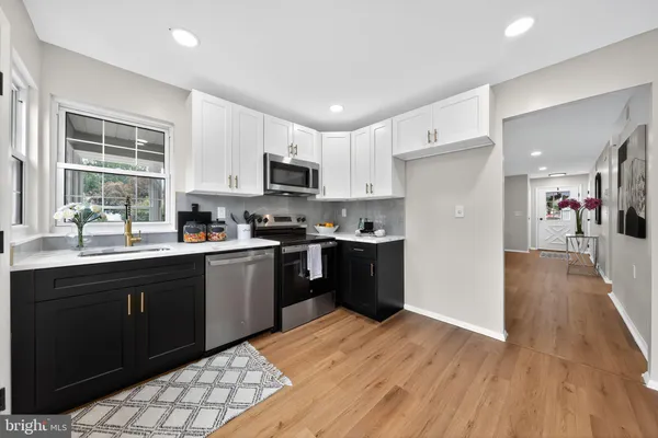 a kitchen with stainless steel appliances granite countertop a refrigerator a sink dishwasher a stove and a oven with wooden floor