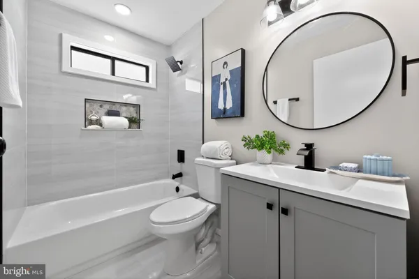 a bathroom with a toilet a sink a tub and a mirror