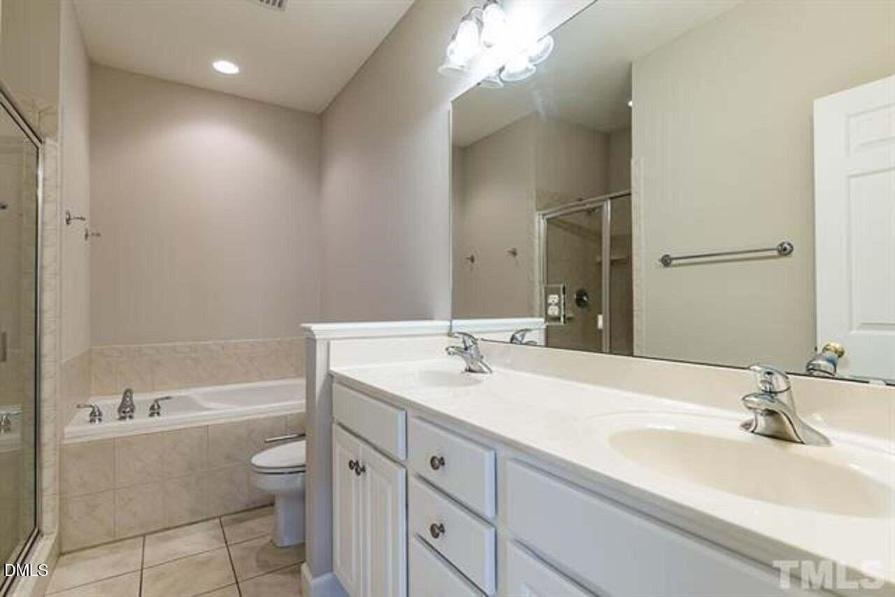 1216 Colonial Club Road Wake Forest, NC 27587 - Photo 17 of 26 a bathroom with a sink a toilet a tub and a mirror